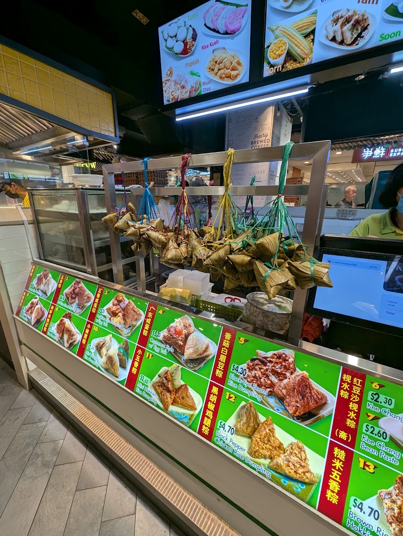 A food stall displaying various traditional rice dumplings (bak chang) and other Asian delights.