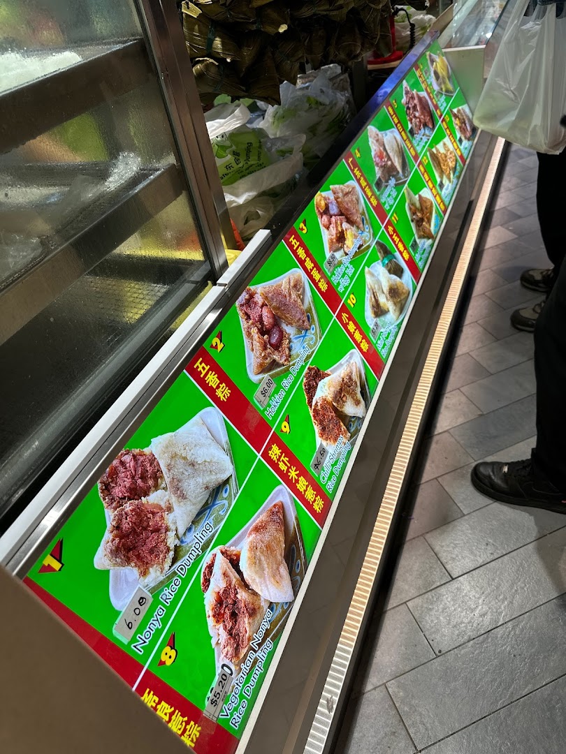 A brightly lit display showcasing various types of traditional rice dumplings with prices.