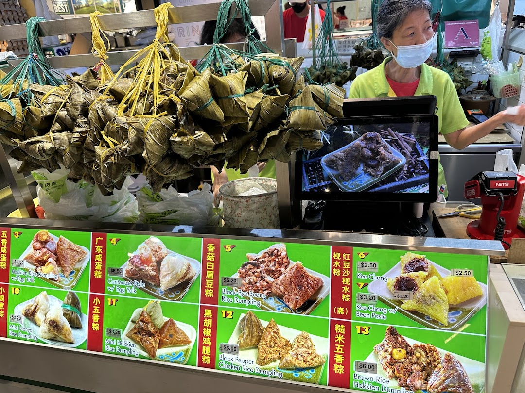 A vendor at Eastern Rice Dumpling stall with various rice dumplings and a detailed menu.