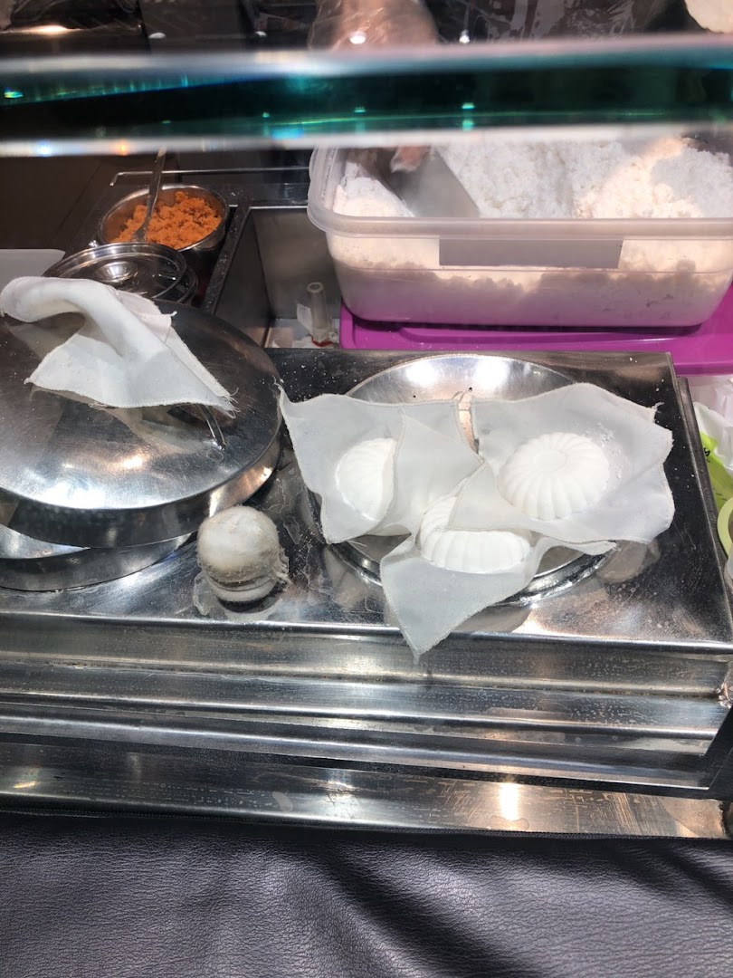 Freshly prepared white steamed cakes or dumplings displayed on a metal counter with ingredients.
