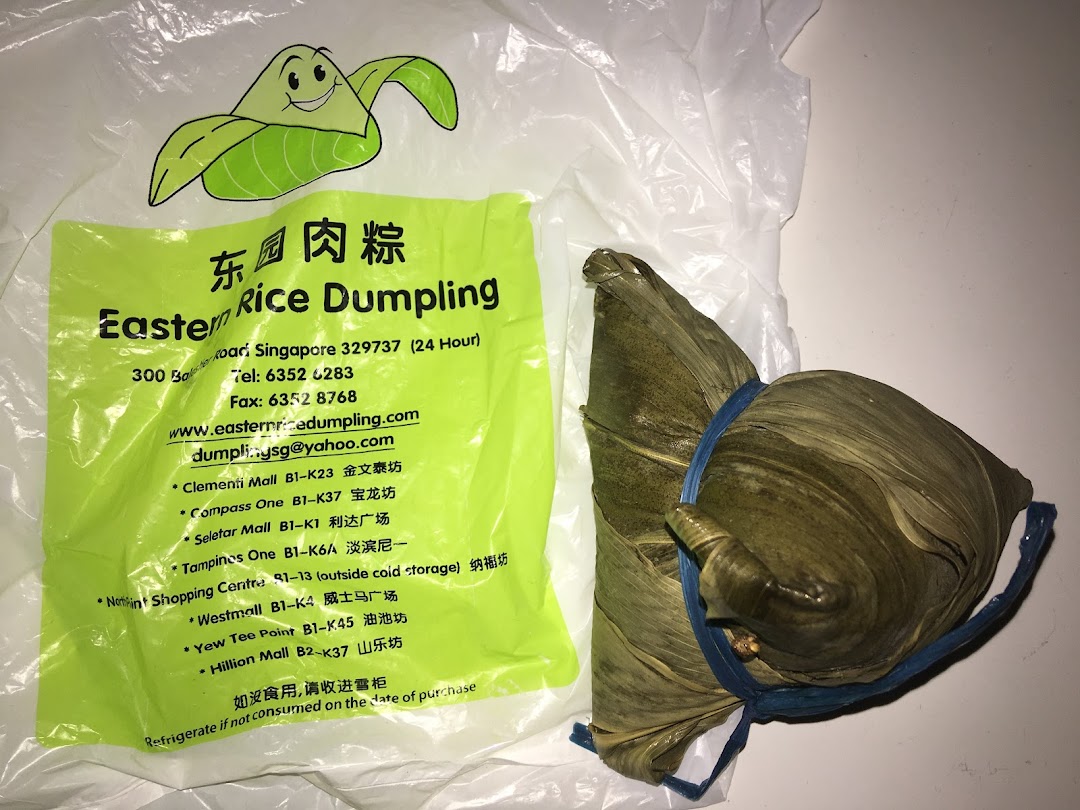 Two traditional rice dumplings next to a branded plastic bag from Eastern Rice Dumpling.