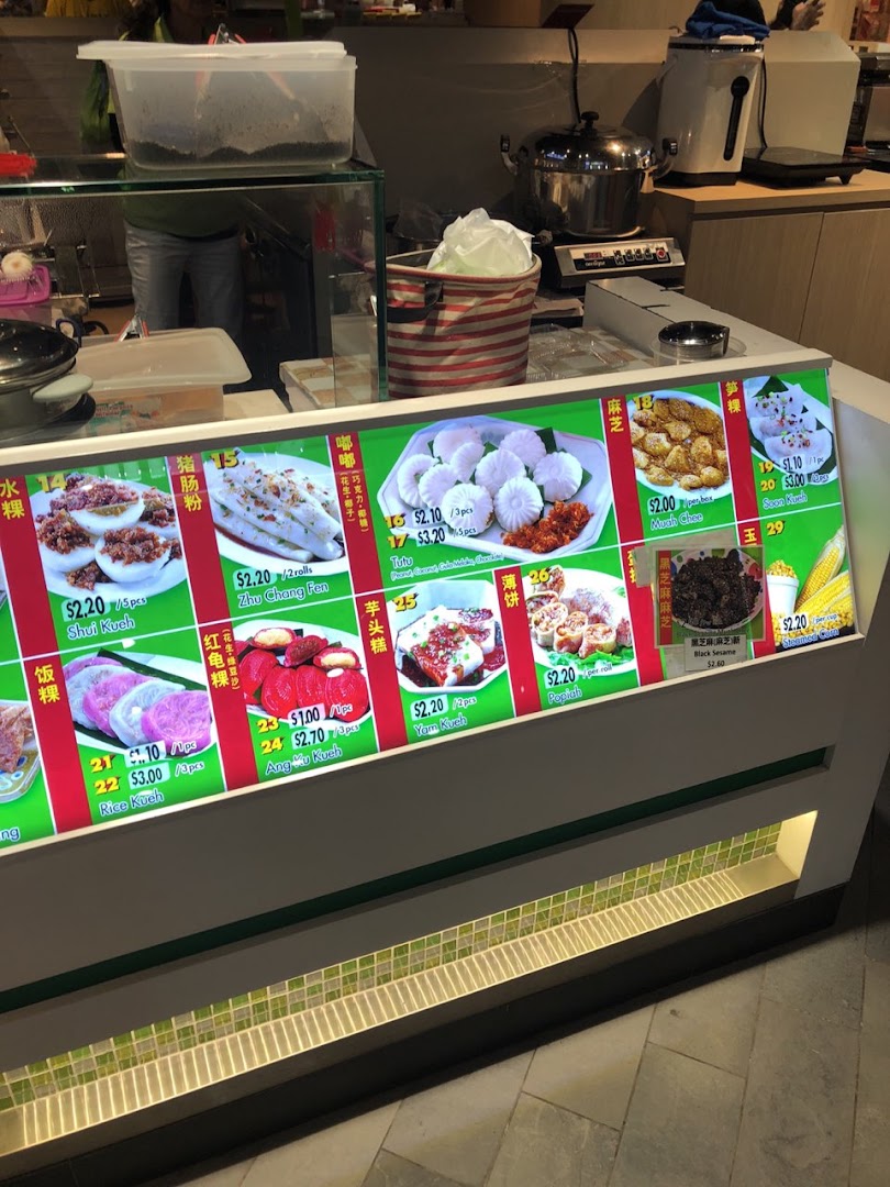A vibrant display counter showcasing various traditional Asian snacks and their prices.