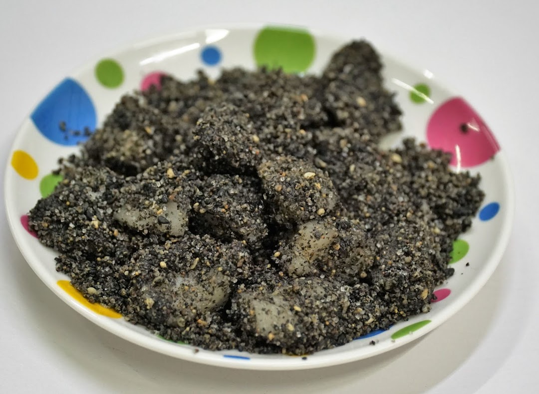 A plate of traditional rice cakes coated generously with black sesame and sugar.