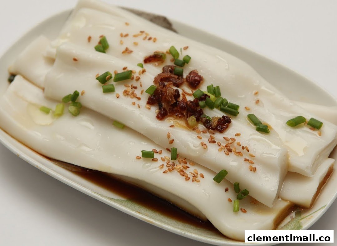 A close-up of delicious rice rolls (Cheung Fun) with sauce, sesame seeds, and green onions.