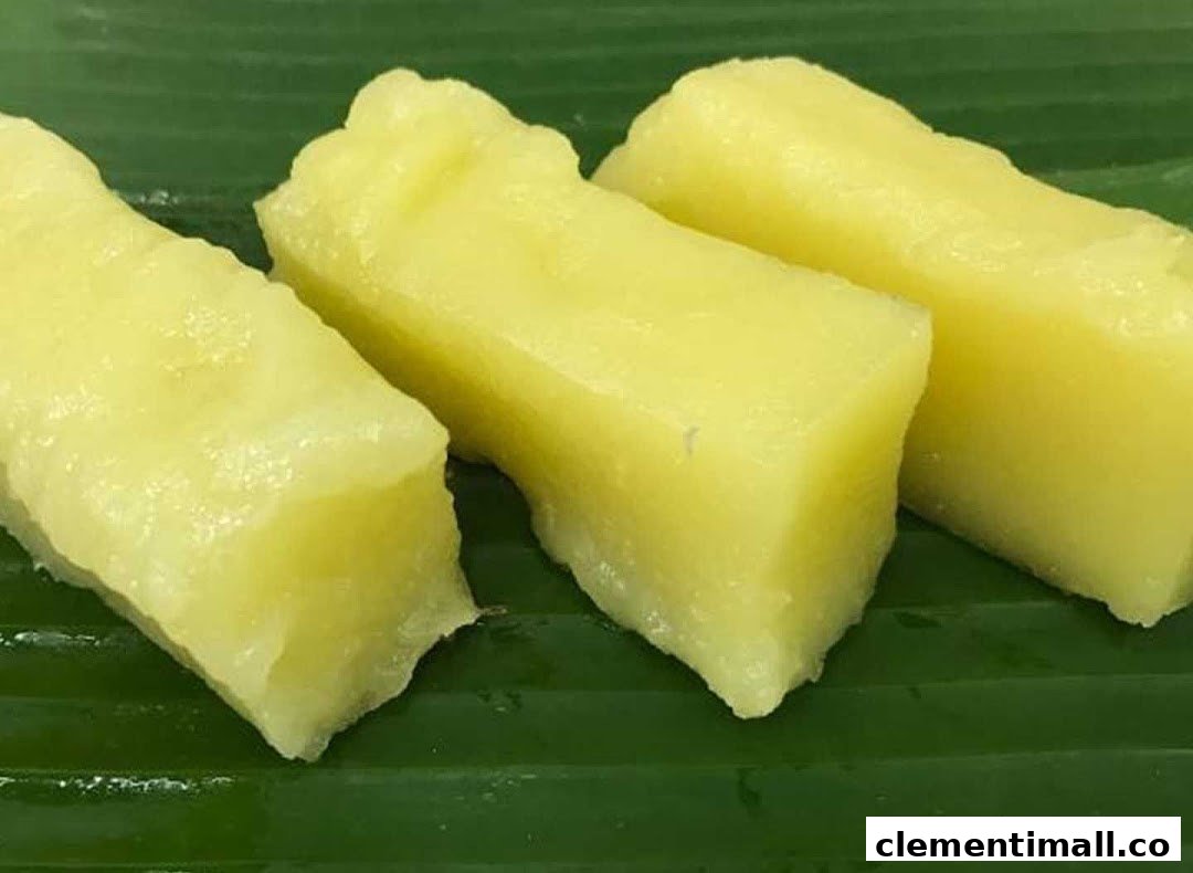 Three pieces of yellow, rectangular sweet treats or cakes on a green banana leaf.