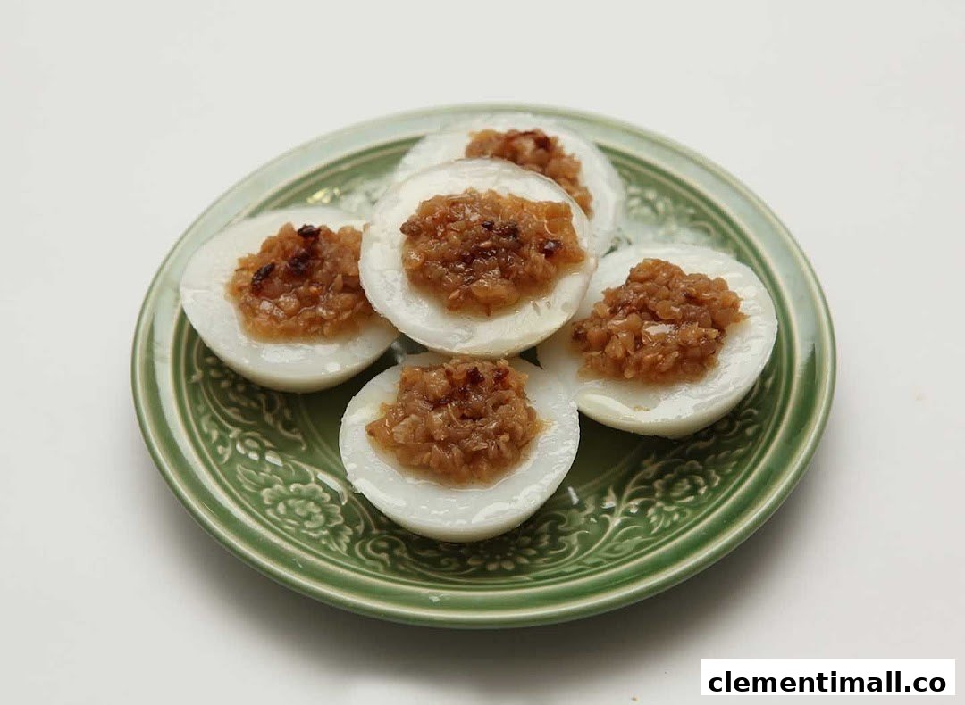 A green plate holds several white steamed rice cakes topped with savory brown minced ingredients.