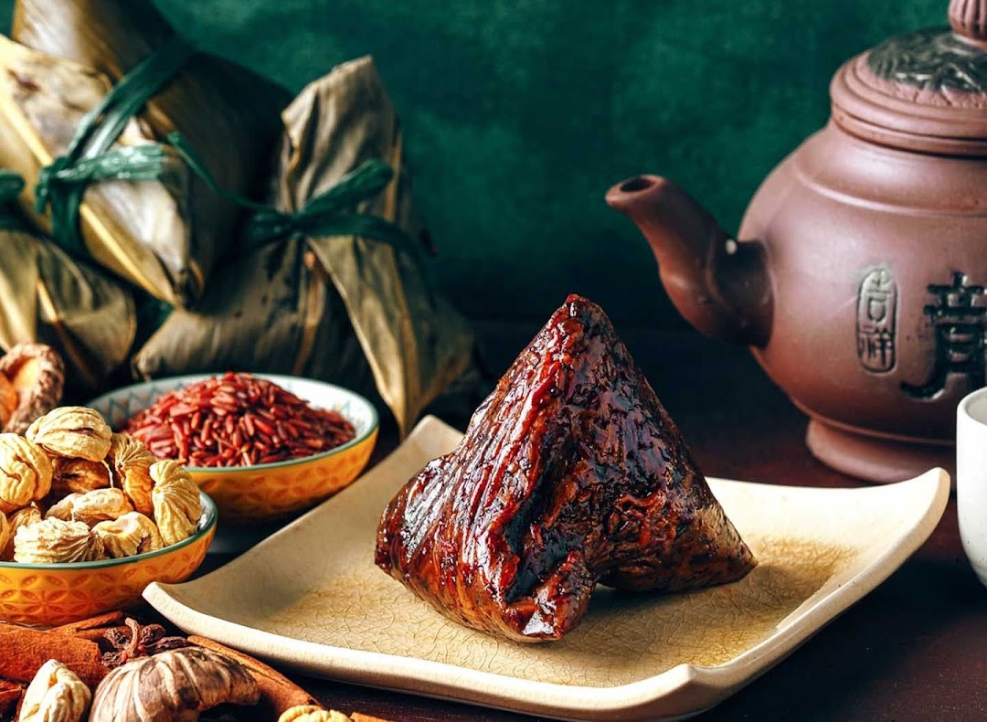 A delicious rice dumpling on a plate with raw ingredients and a traditional teapot.