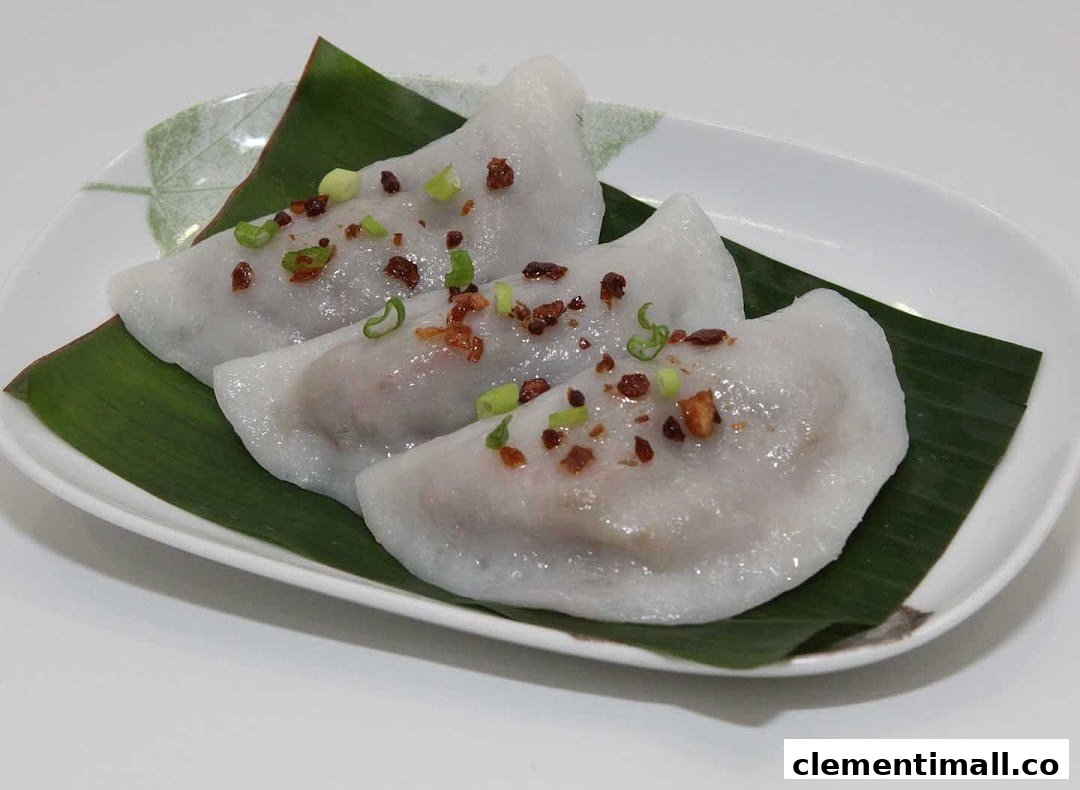 Three steamed dumplings with fried shallots and green onions on a banana leaf.
