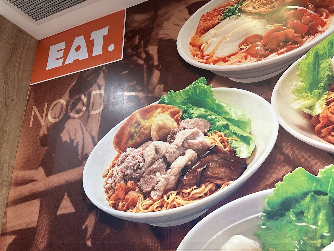 A vibrant wall display showcasing various delicious noodle dishes from the 'EAT.' shop.