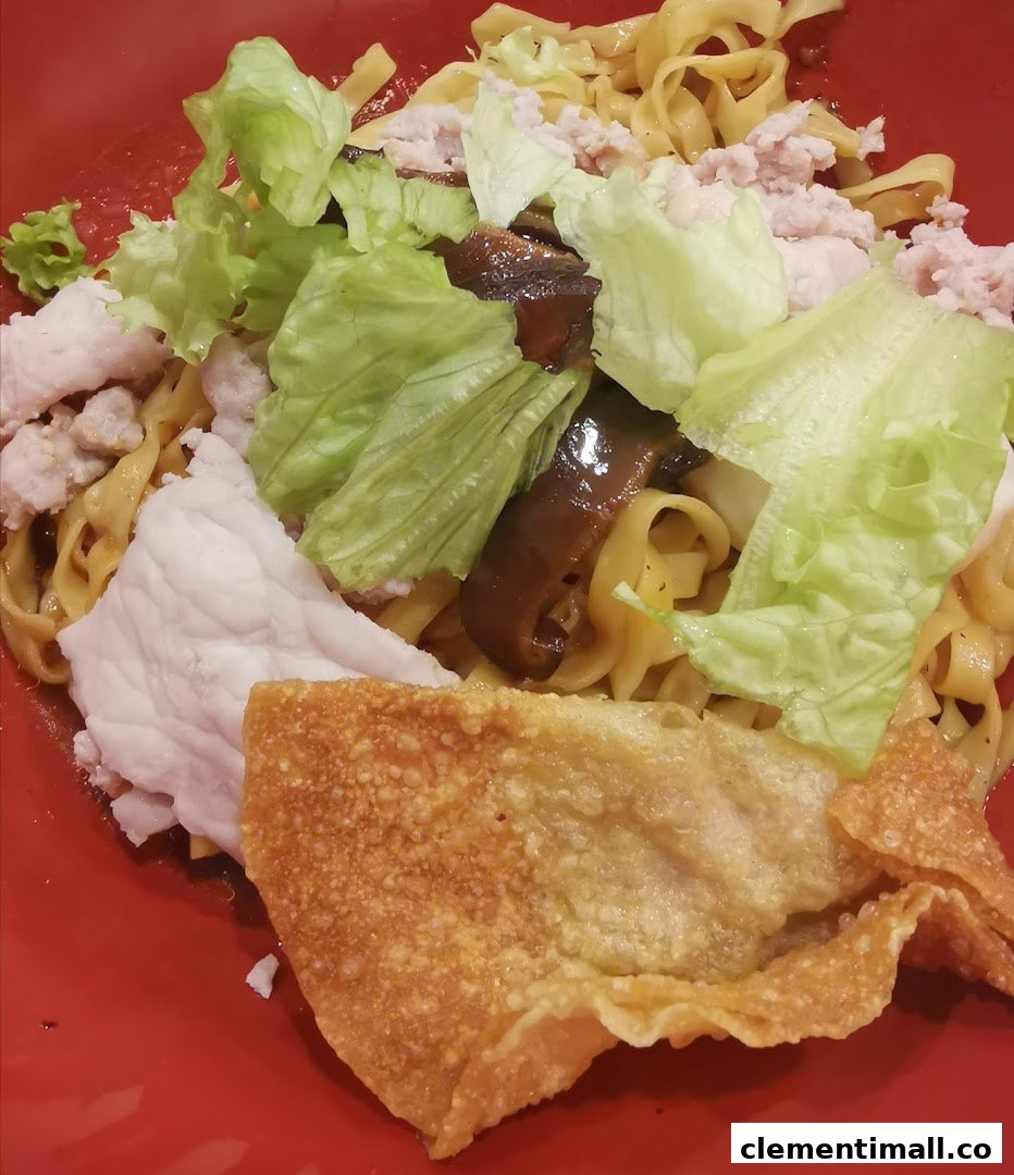 A vibrant red bowl filled with noodles, topped with chicken, lettuce, mushrooms, and crispy wonton.