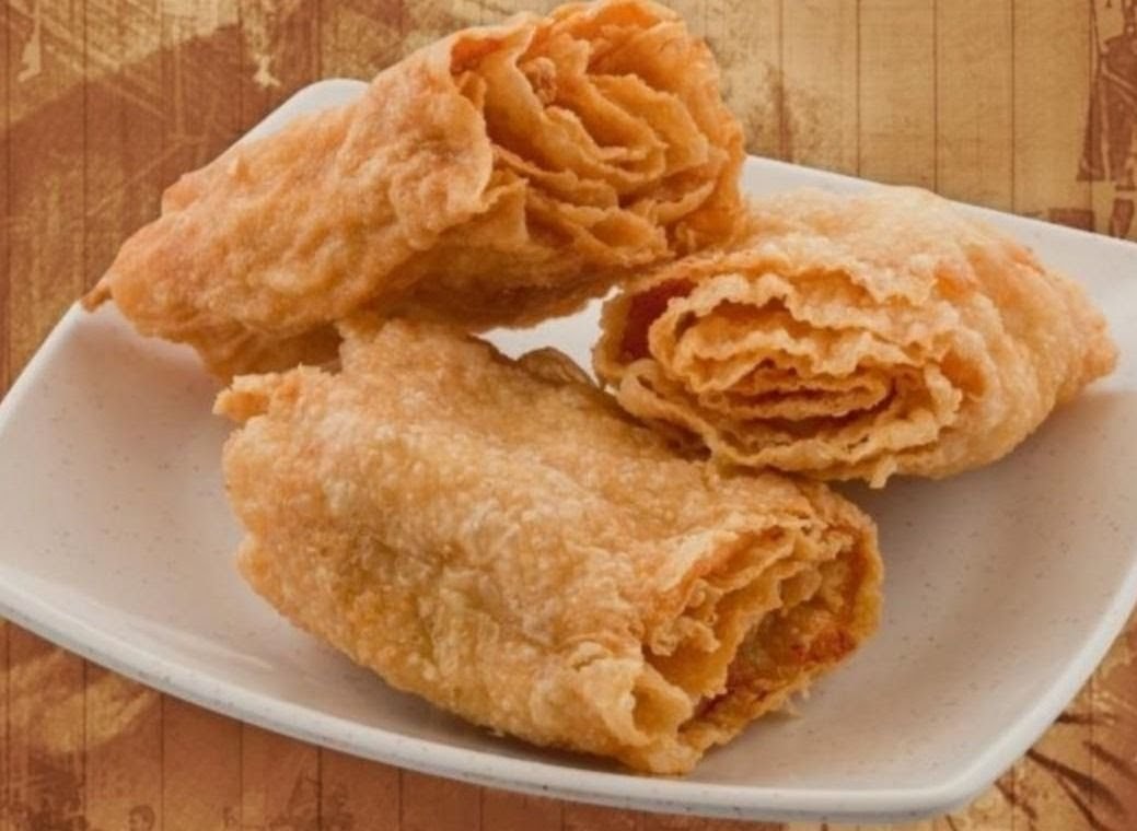 Three golden-brown fried pastries or rolls are presented on a white rectangular plate.
