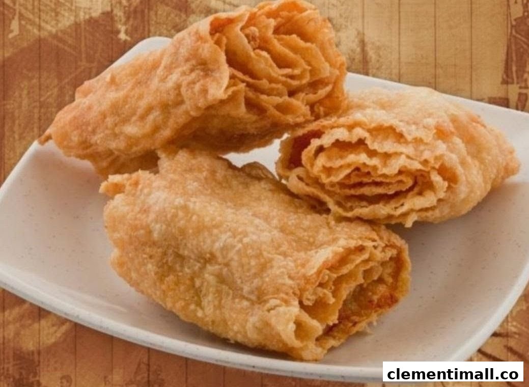 Three golden-brown fried pastries or rolls are presented on a white rectangular plate.