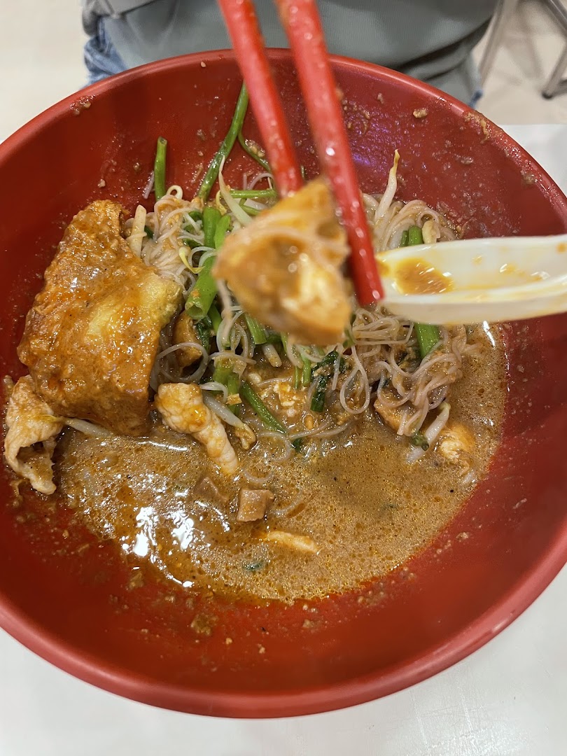 A close-up of a delicious bowl of noodles with broth, vegetables, and tofu being enjoyed with chopsticks.