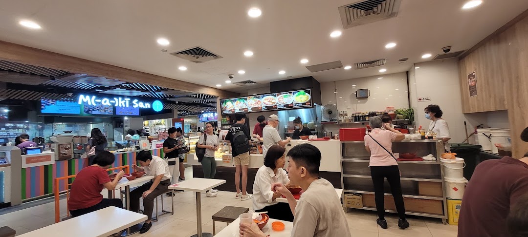 A lively food court scene at EAT, featuring customers enjoying meals and ordering from various food stalls.