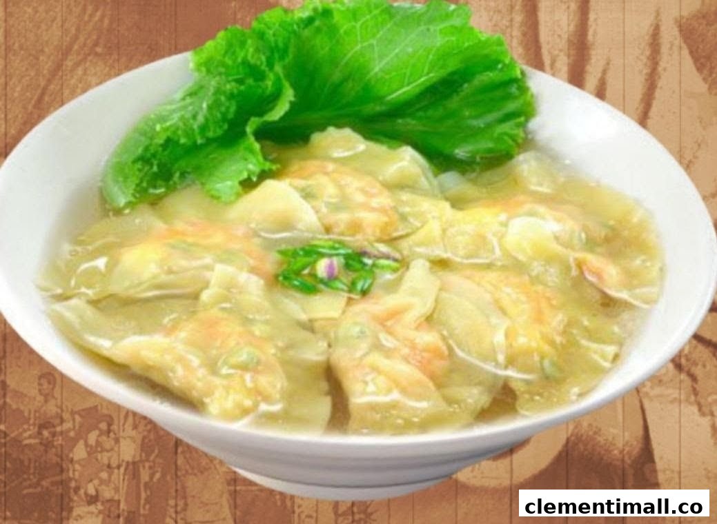 A close-up of a bowl of savory dumplings or wontons in broth, garnished with fresh lettuce.