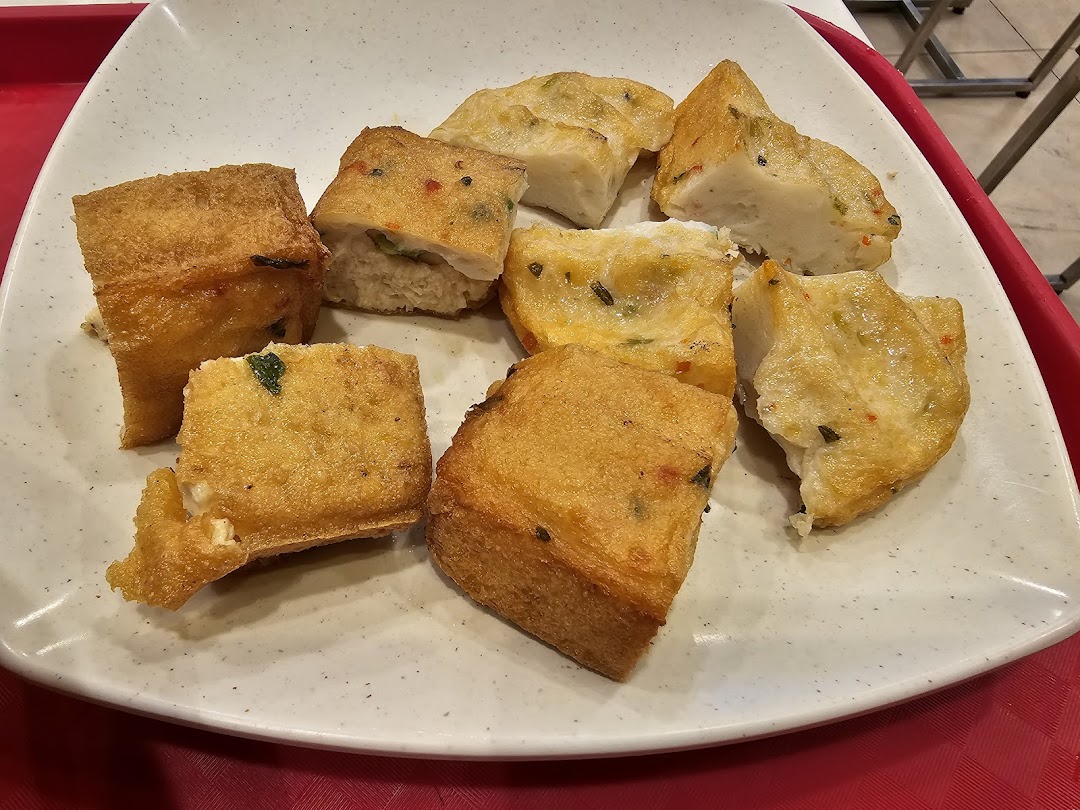 A plate filled with various golden-fried items, resembling fish cakes or stuffed tofu, ready to be eaten.