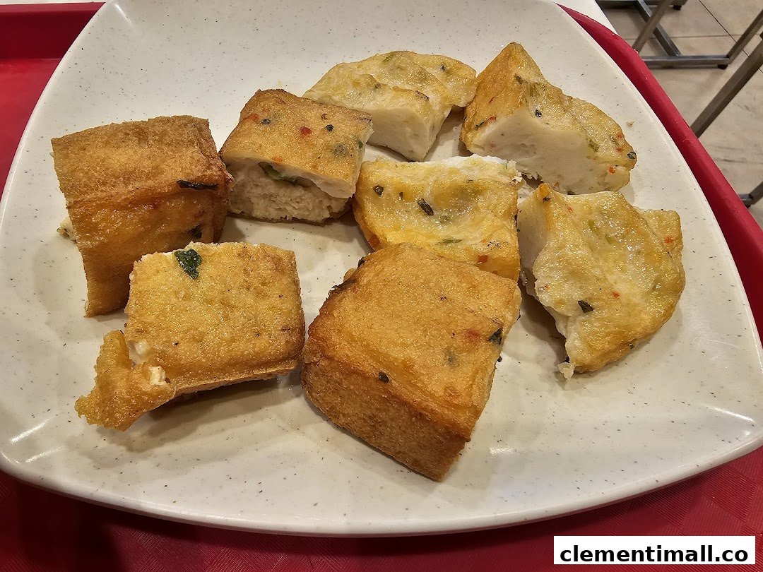 A plate filled with various golden-fried items, resembling fish cakes or stuffed tofu, ready to be eaten.