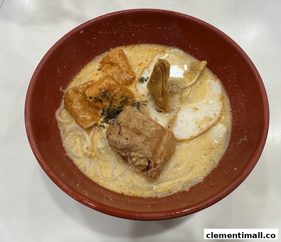A close-up of a delicious bowl of creamy noodle soup with various toppings in a red bowl.