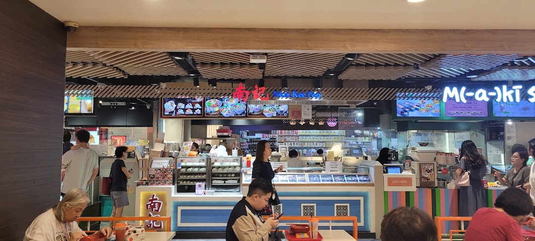 A lively food court scene featuring multiple eateries, including Nam Kee Pau, with customers dining and ordering.