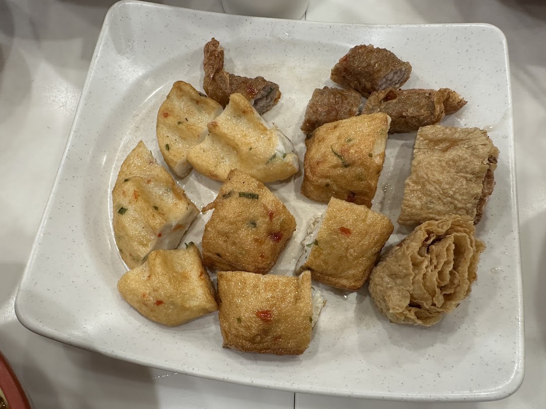 A white plate filled with various fried Asian snacks, including fish cakes and bean curd rolls.