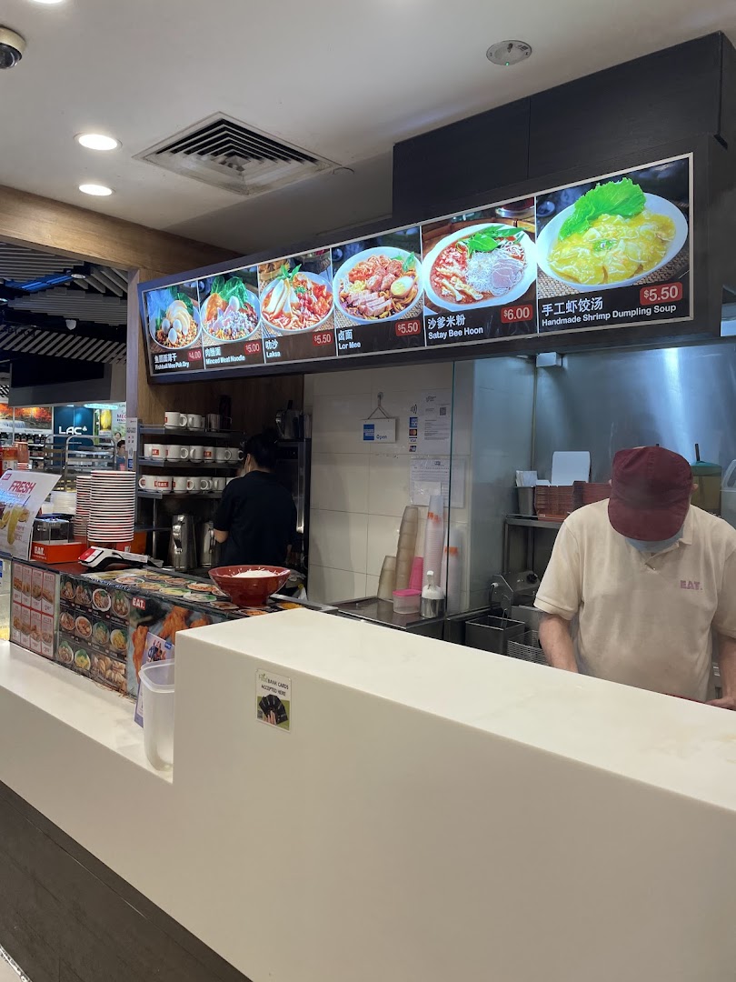 A food stall at EAT. featuring a digital menu board with various noodle and dumpling dishes.