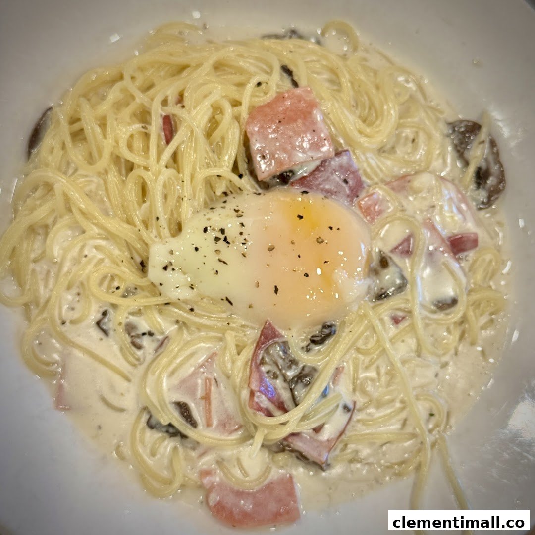 A creamy pasta dish with spaghetti, bacon, mushrooms, and a perfectly poached egg.