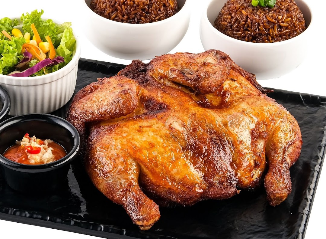 A perfectly roasted whole chicken served with flavorful rice, fresh salad, and dipping sauce.