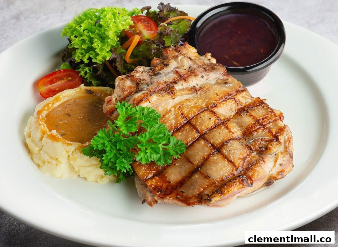 A grilled chicken steak served with mashed potatoes, fresh salad, and a side of sauce.