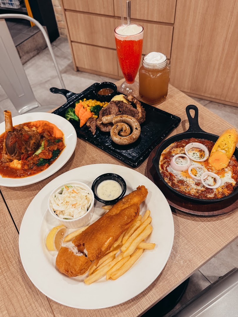 A table laden with various delicious dishes including fish and chips, lamb shank, and a mixed grill.