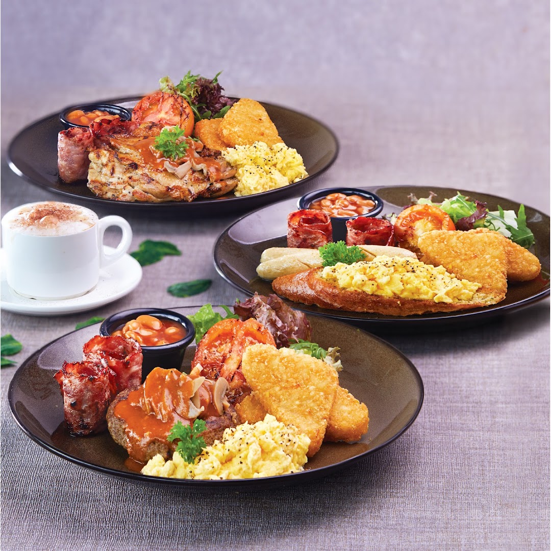Three hearty breakfast/brunch plates featuring eggs, hash browns, meats, and beans, with a coffee cup.