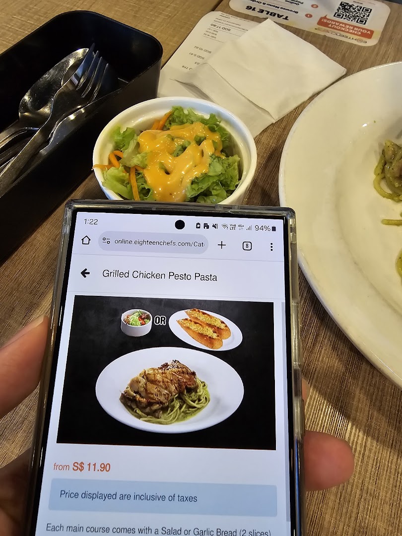 A diner's view of a table setting with a side salad and a phone displaying a menu item.