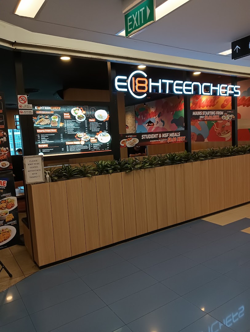 Brightly lit entrance of Eighteen Chefs restaurant, featuring its logo and promotional posters.