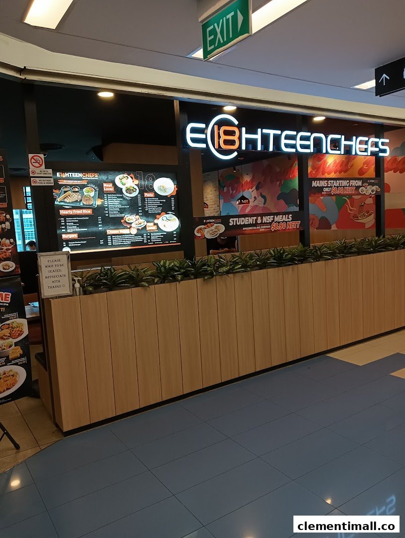 Brightly lit entrance of Eighteen Chefs restaurant, featuring its logo and promotional posters.