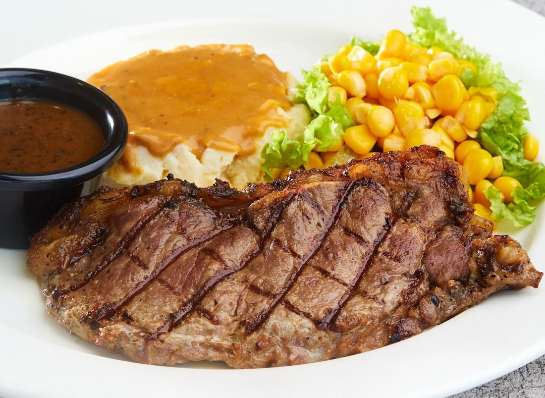 A grilled steak served with mashed potatoes, gravy, and corn on a white plate.