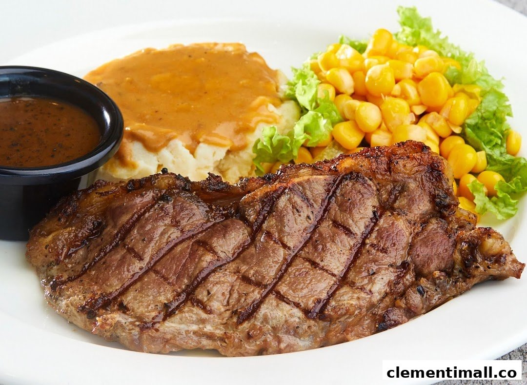 A grilled steak served with mashed potatoes, gravy, and corn on a white plate.