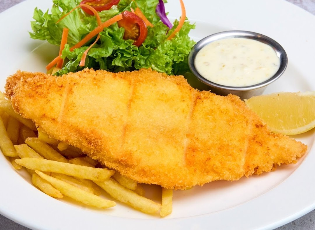A plate of golden-fried fish and chips with a side salad, lemon wedge, and tartar sauce.