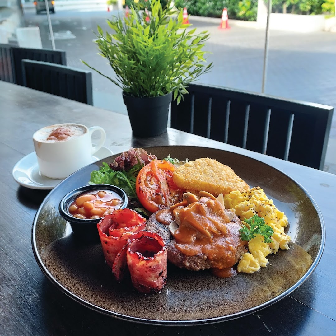 A hearty breakfast plate with steak, eggs, bacon, hash brown, and beans, served with coffee.