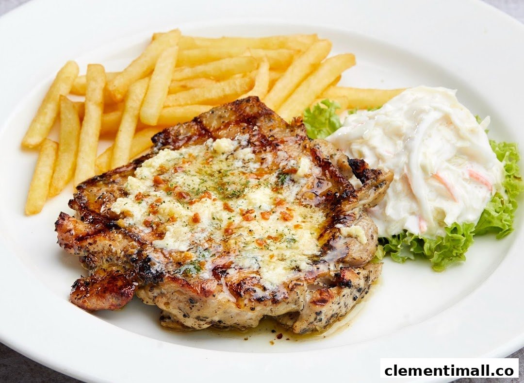 A grilled chicken chop topped with cheese and herbs, served with fries and coleslaw on a white plate.
