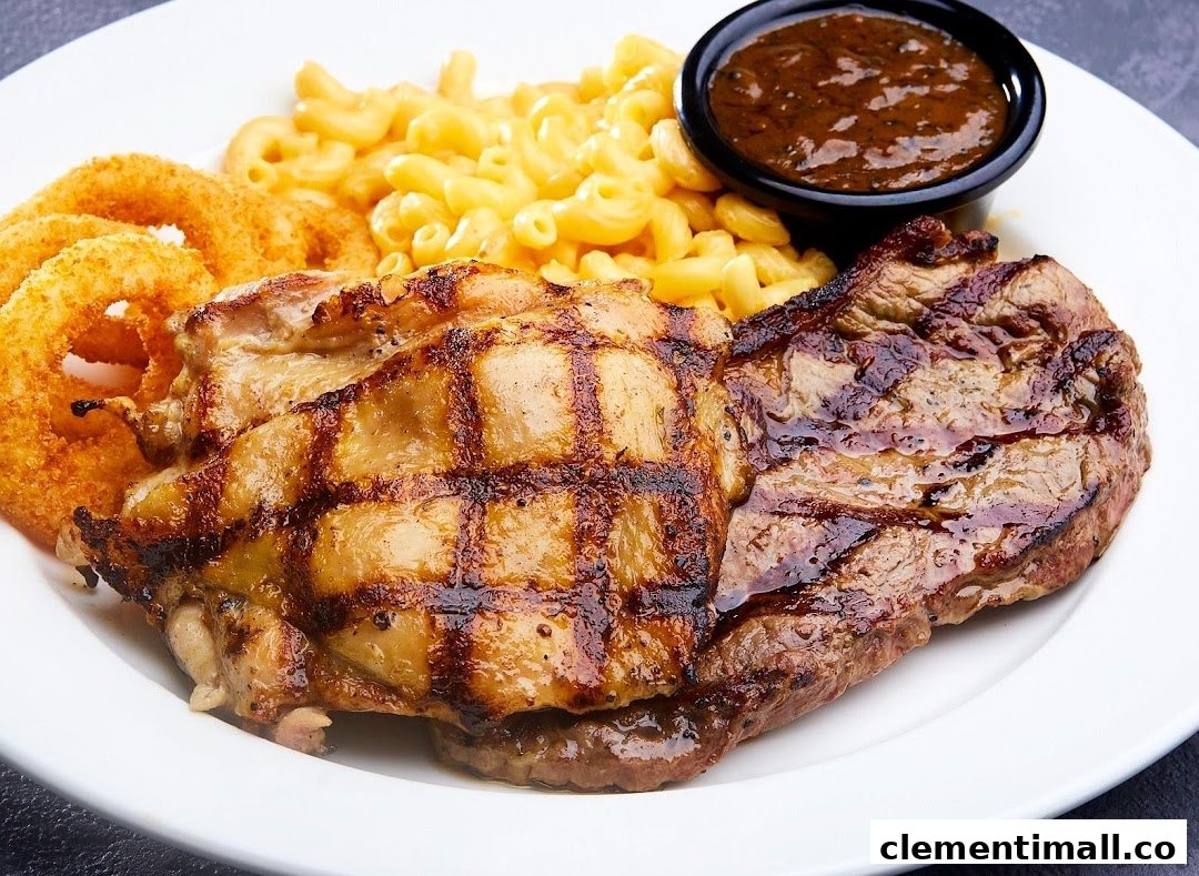 A delicious plate featuring grilled chicken, steak, mac & cheese, onion rings, and sauce.