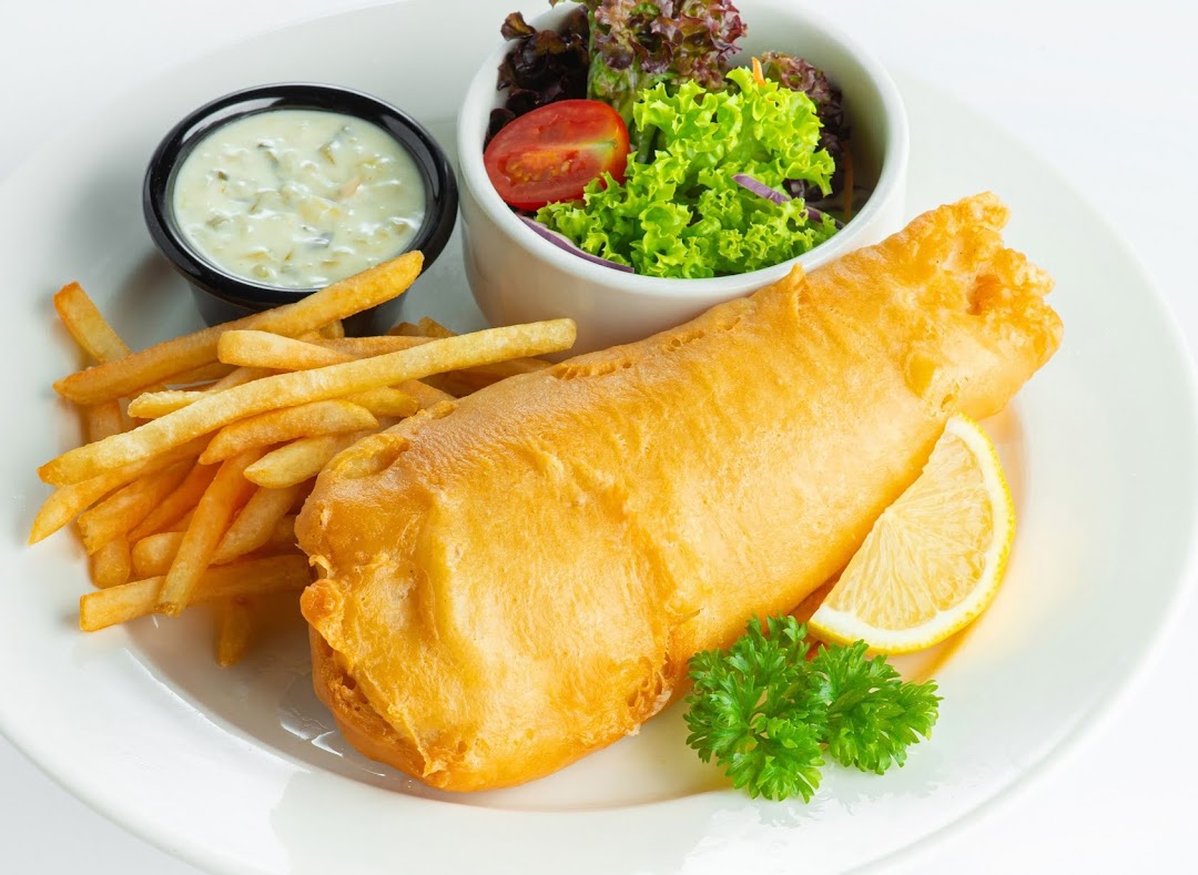 A classic fish and chips dish served with golden fries, fresh salad, and tartar sauce.