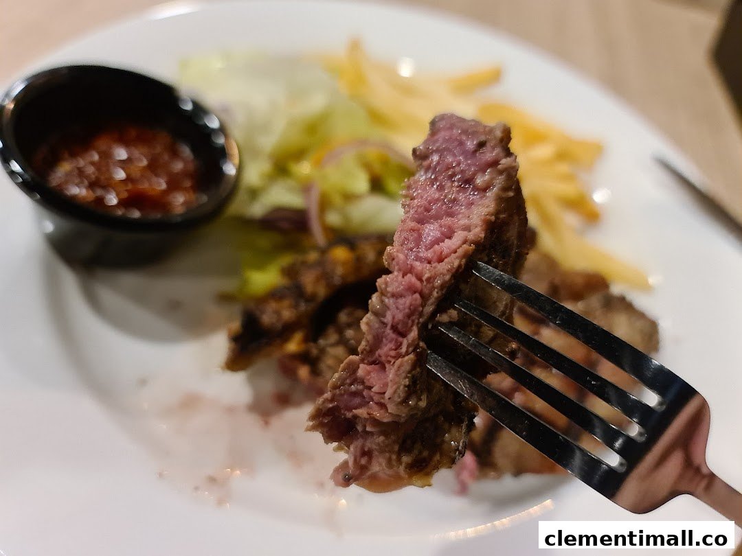 A close-up of a perfectly cooked steak on a fork, served with fries and salad.