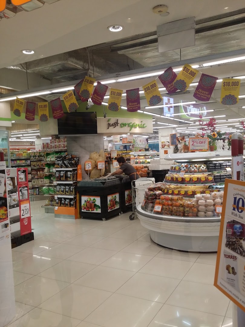 An interior view of FairPrice Finest, showcasing fresh produce, organic section, and a staff member.