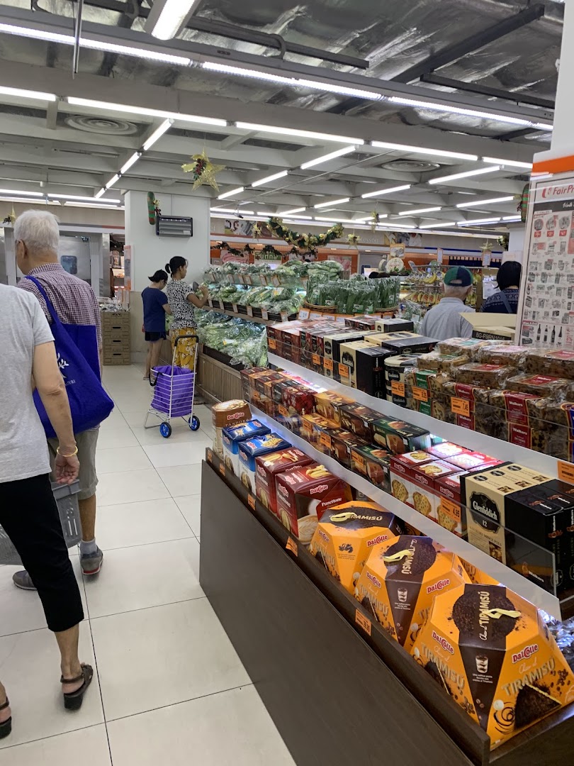 An interior view of FairPrice Finest supermarket, showing aisles with fresh produce and packaged goods, with shoppers browsing.
