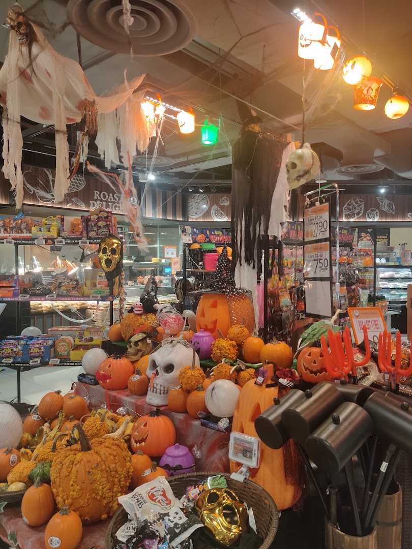 A vibrant Halloween display with pumpkins, skulls, and spooky decorations inside FairPrice Finest.