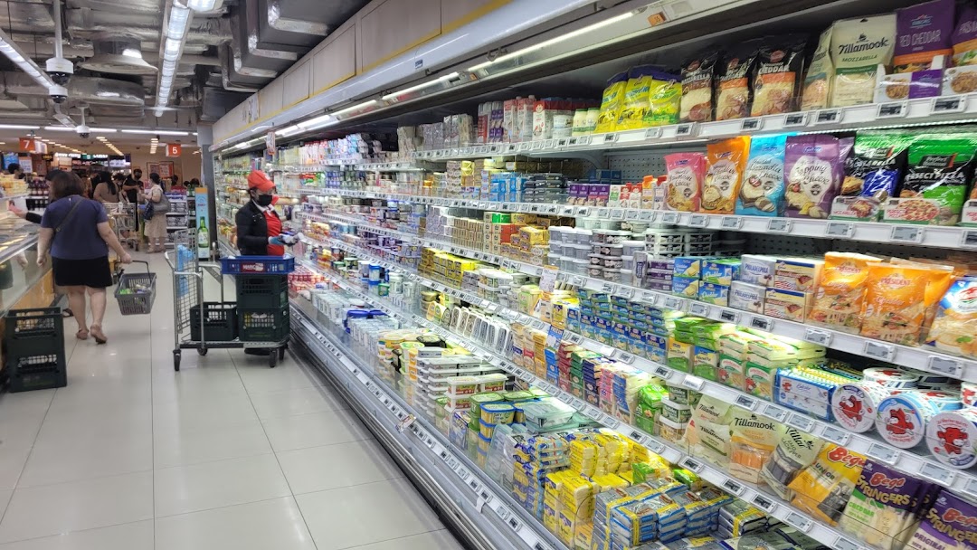 A wide aisle in FairPrice Finest supermarket, showcasing refrigerated dairy and cheese products.