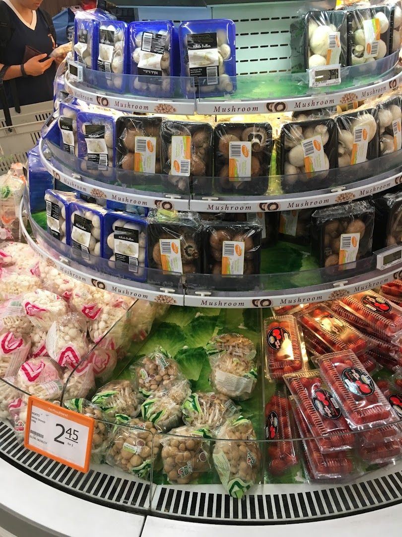 A multi-tiered display of fresh packaged mushrooms and other produce in a supermarket.