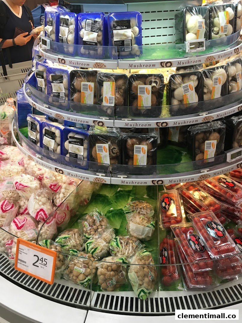 A multi-tiered display of fresh packaged mushrooms and other produce in a supermarket.