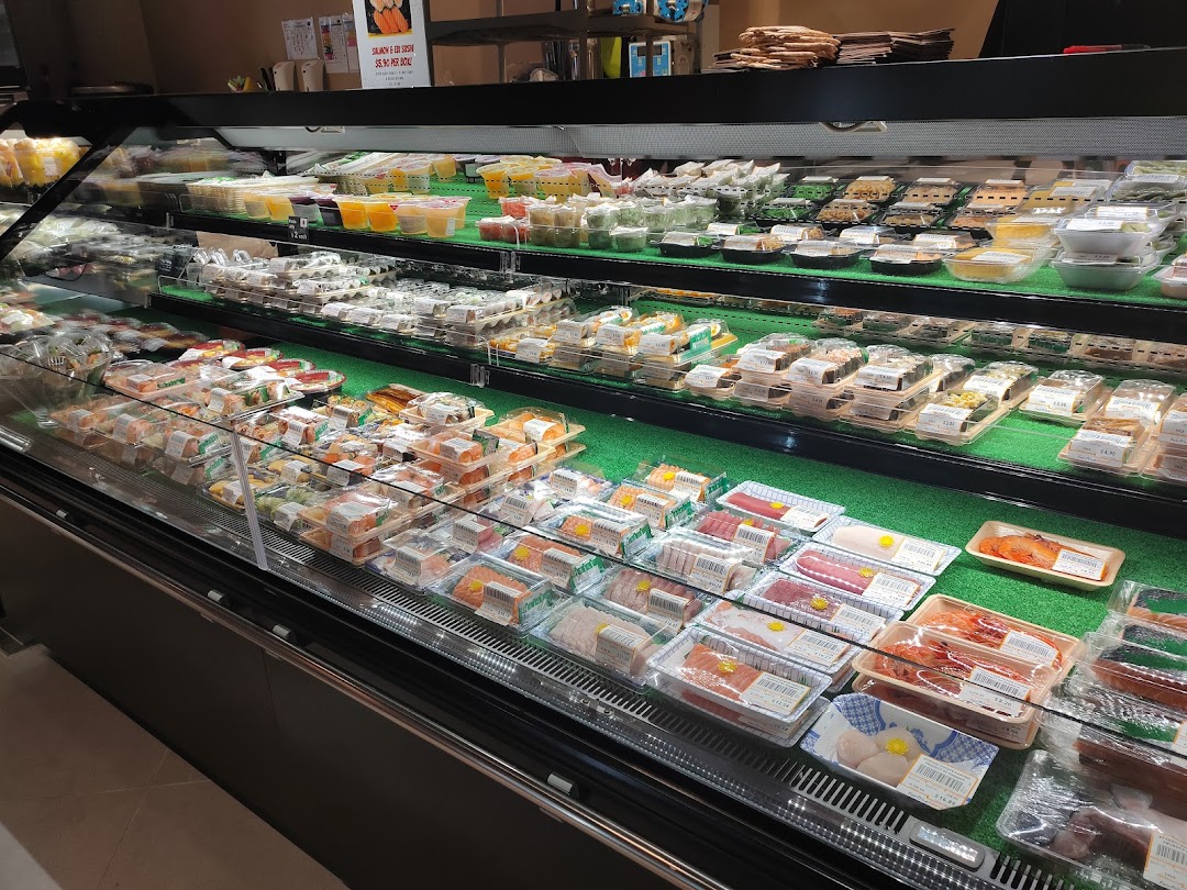 A refrigerated display case showcasing a wide variety of fresh sushi, sashimi, and pre-packaged meals.