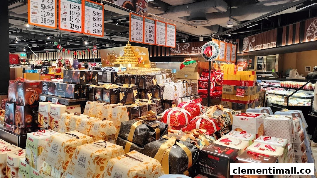 A supermarket aisle showcasing a wide array of festive cakes, panettone, and gourmet gift sets, with overhead price signs.