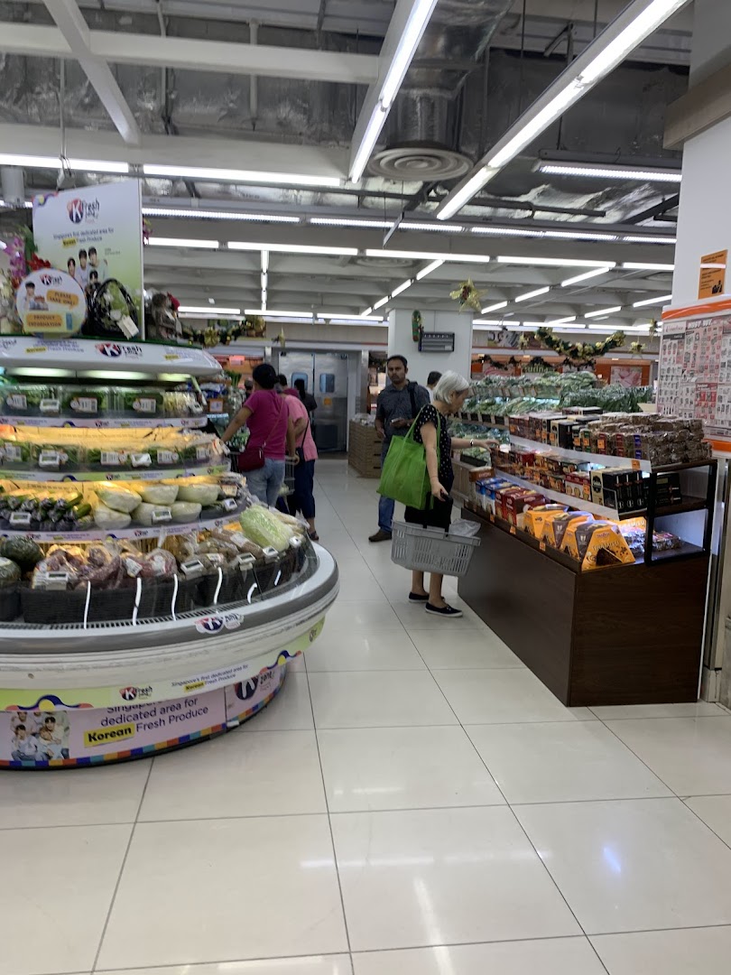 Shoppers browse fresh produce and packaged goods in a well-lit supermarket aisle.